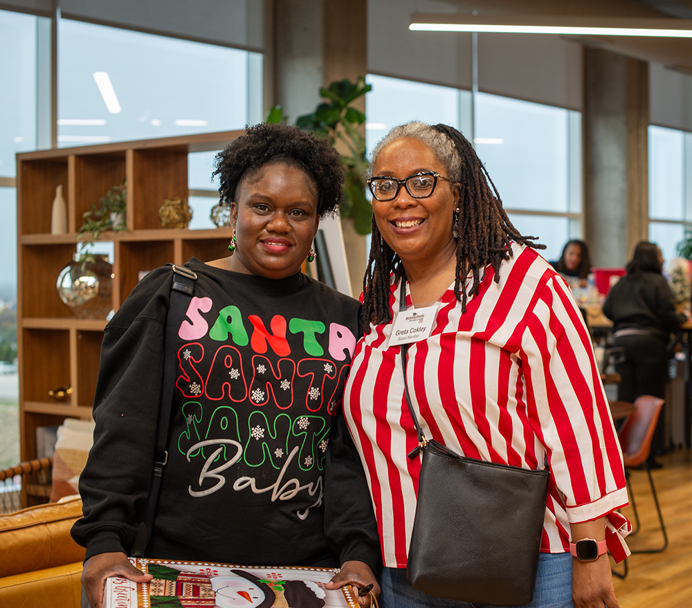 Photo of two smiling women gift wrapping for holidays